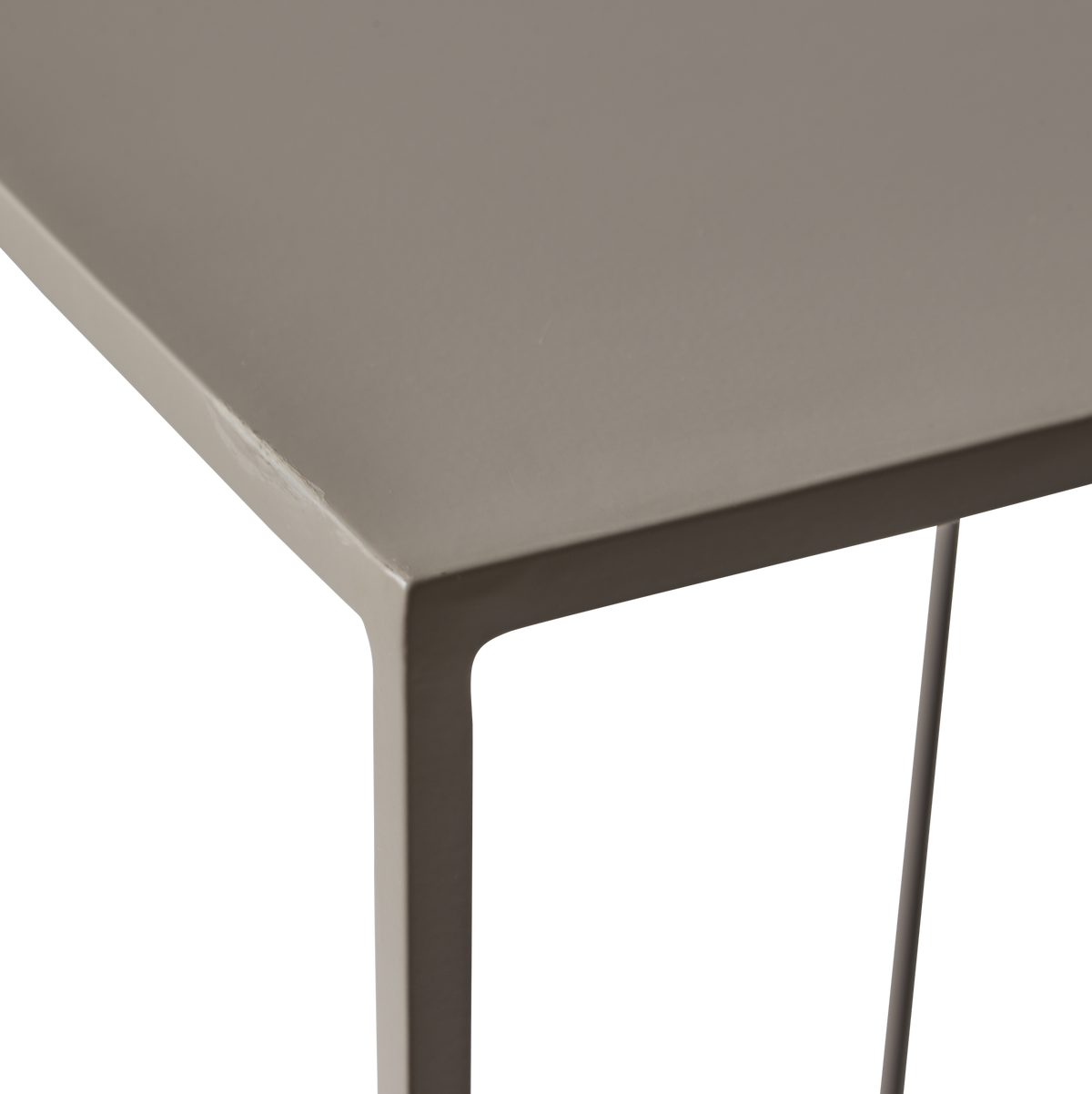 Nærbillede af hjørne på taupefarvet metalbord med slanke ben.