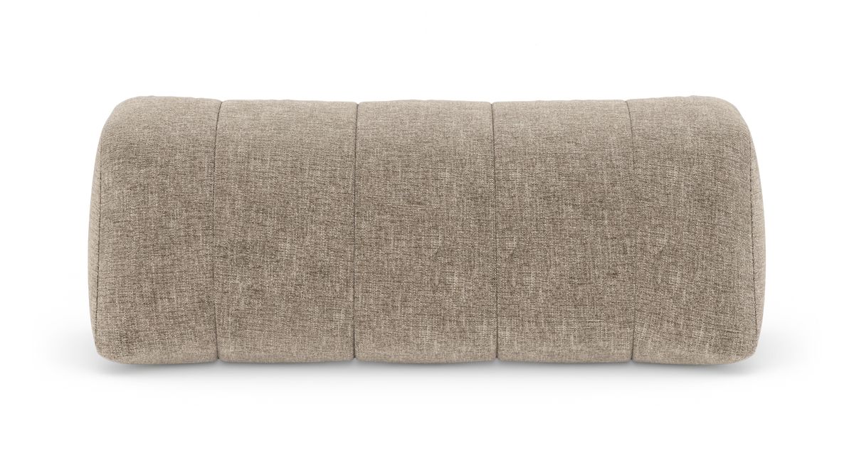 Beige tekstilbetrukket ottoman/skammel med blødt afrundet form og lodrette, segmenterede syninger, fritlagt på hvid baggrund.
