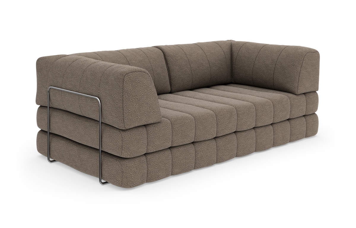 Brun, lav modulsofa med bred kanalstikning og metalbøjle på siden, frilagt mod hvid baggrund.