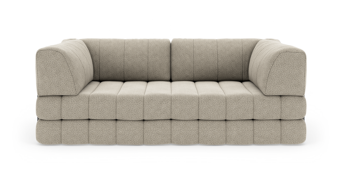 Beige modulsofa med afrundede armlæn i bouclé-lignende stof, fotograferet forfra på hvid baggrund.