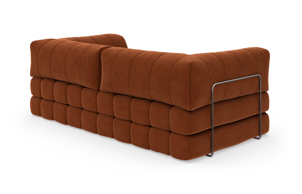 Rustfarvet modulsofa med quiltet, puffet polstring set bagfra i studie.