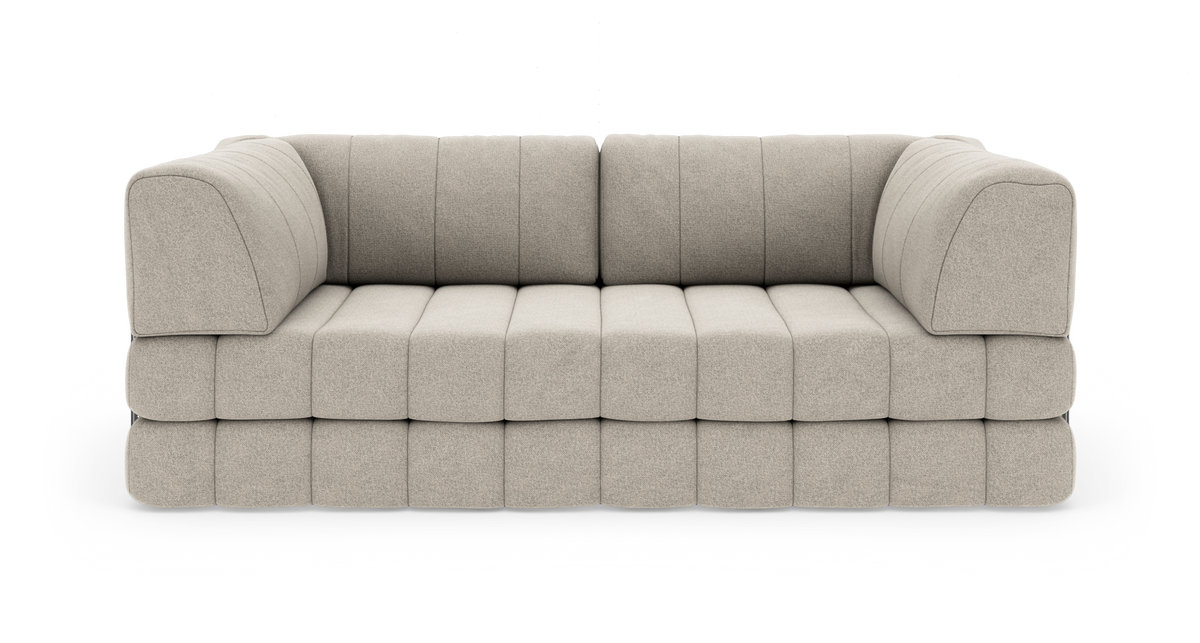 Beige modulsofa med blød, vatteret sæde og afrundede armlæn på hvid baggrund.