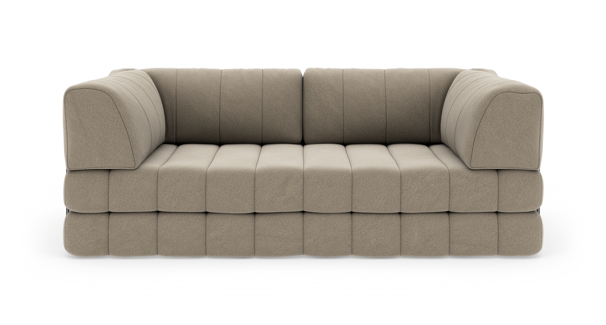Beige modulsofa med blødt, quiltet sæde og afrundede armlæn, fritlagt på hvid baggrund.