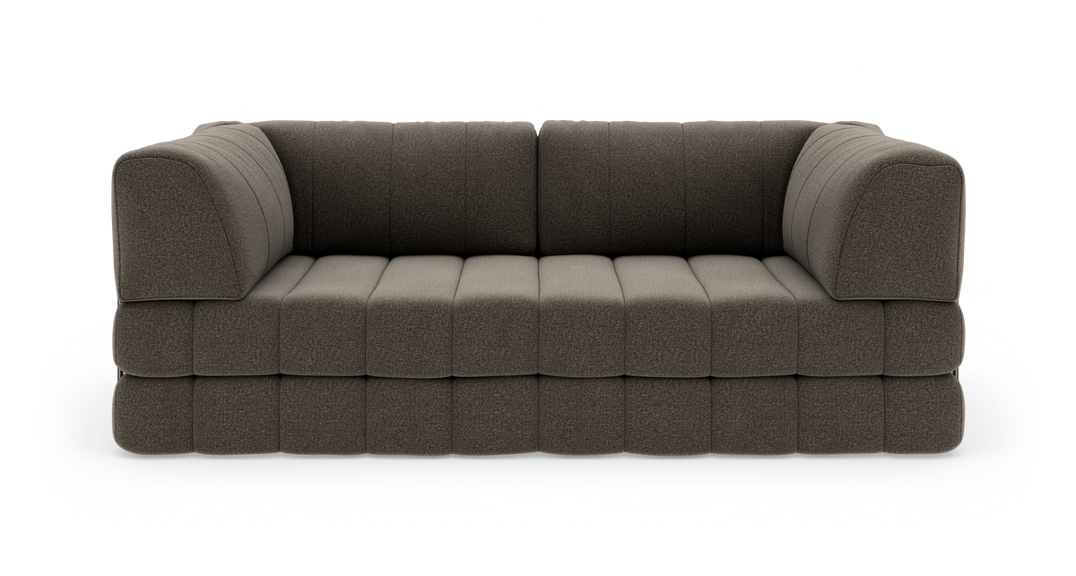Modulsofa i mørkegrå/brun tekstil med dybe quiltede sæder og afrundede armlæn, fritlagt på hvid baggrund.