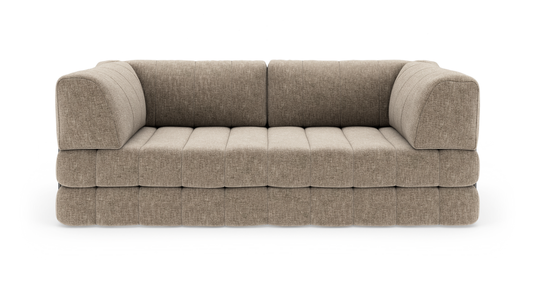 Beige modulsofa i stof med bløde, afrundede armlæn og quiltet sæde, vist forfra i studiopsætning.