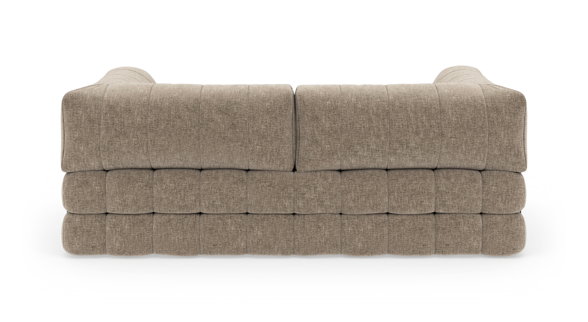 Bagside af en modulær beige stofsofa med dyb tuftning og afrundede armlæn, isoleret på hvid baggrund.