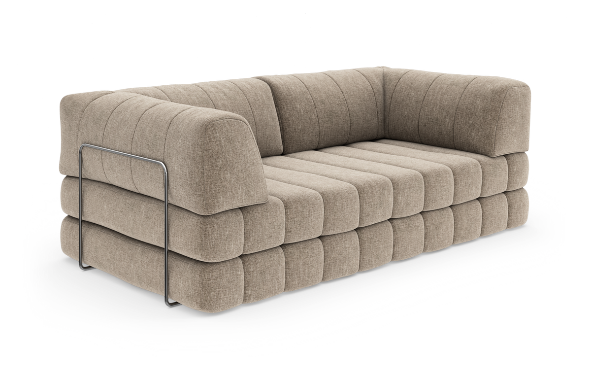 Beige, moderne sofa med brede kanalquiltede puder og afrundede former, med metalramme-detalje på siden, frilagt på hvid baggrund.