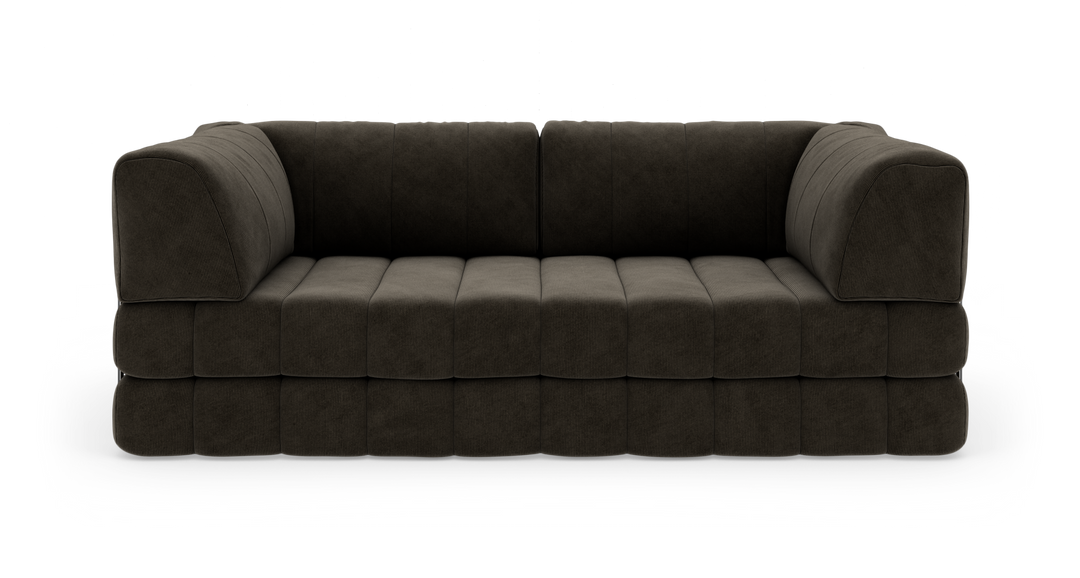 Mørkebrun, modulær 3-personers sofa i bredriflet fløjl, fritlagt på hvid baggrund med bløde, blokformede hynder og afrundede armlæn.