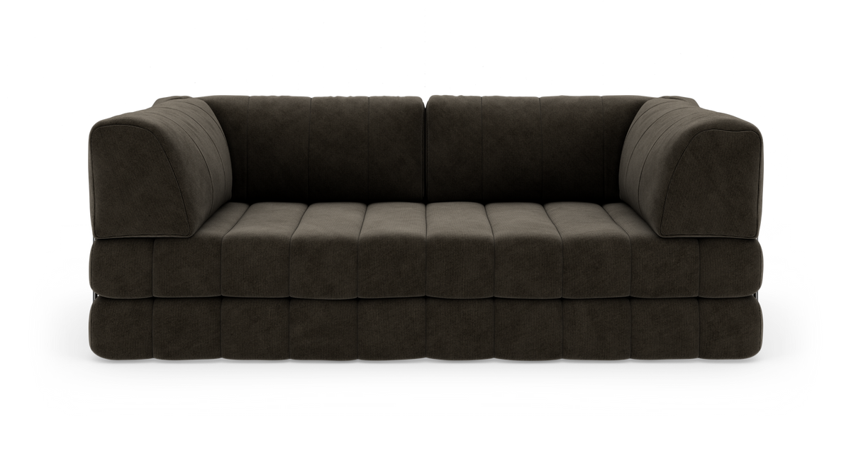Mørkebrun, modulær 3-personers sofa i bredriflet fløjl, fritlagt på hvid baggrund med bløde, blokformede hynder og afrundede armlæn.