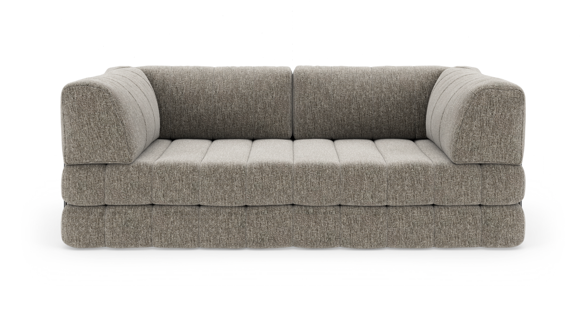 Grå‑beige modulsofa med afrundede armlæn og dybe, kanalsyede sædehynder, frilagt på hvid baggrund.
