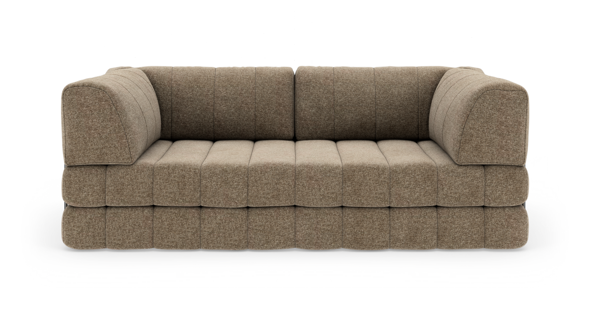 Brun/beige modulsofa med blødt afrundede armlæn og blokquiltede puder, frilagt på hvid baggrund.