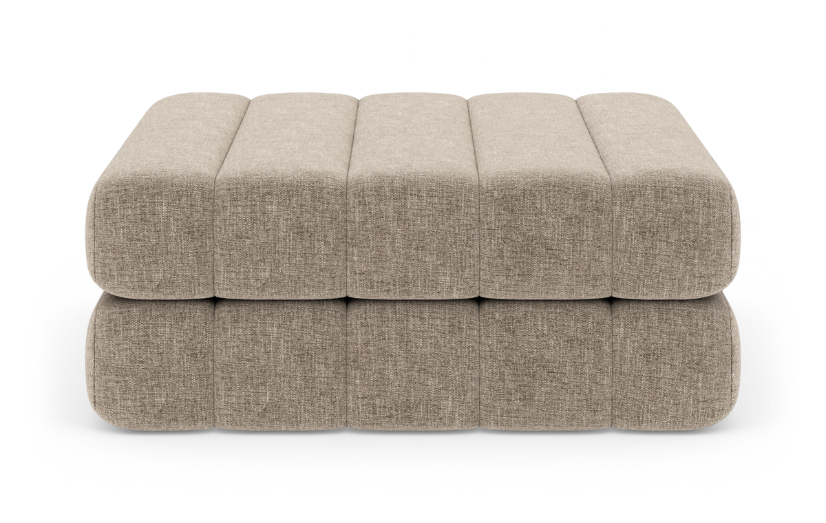 Beige, modulær polstret bænk/ottoman med afrundede kanter, fotograferet lige forfra på hvid baggrund.