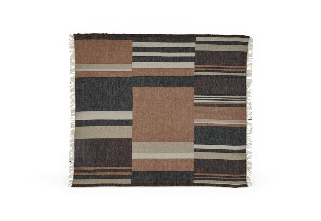 Ternet plaid med blokke og striber i terrakotta, mørkegrå og beige med frynser på kortsiderne.