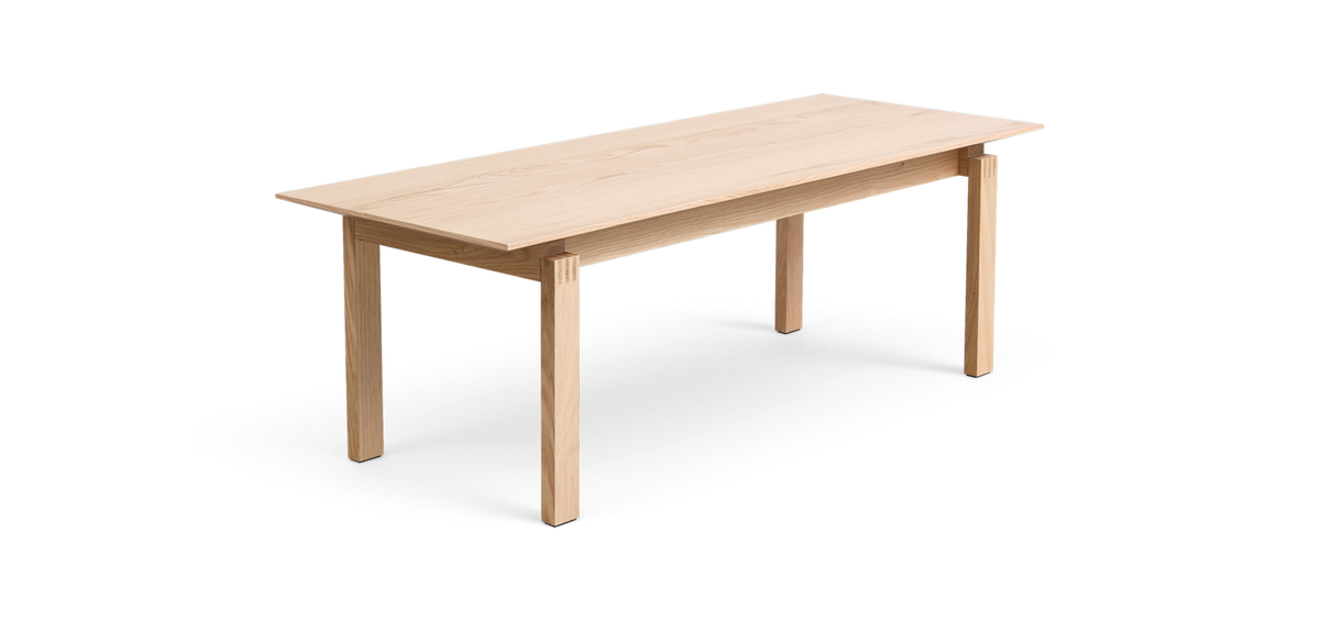Rektangulært spisebord i lys eg med enkel, minimalistisk design på hvid baggrund.