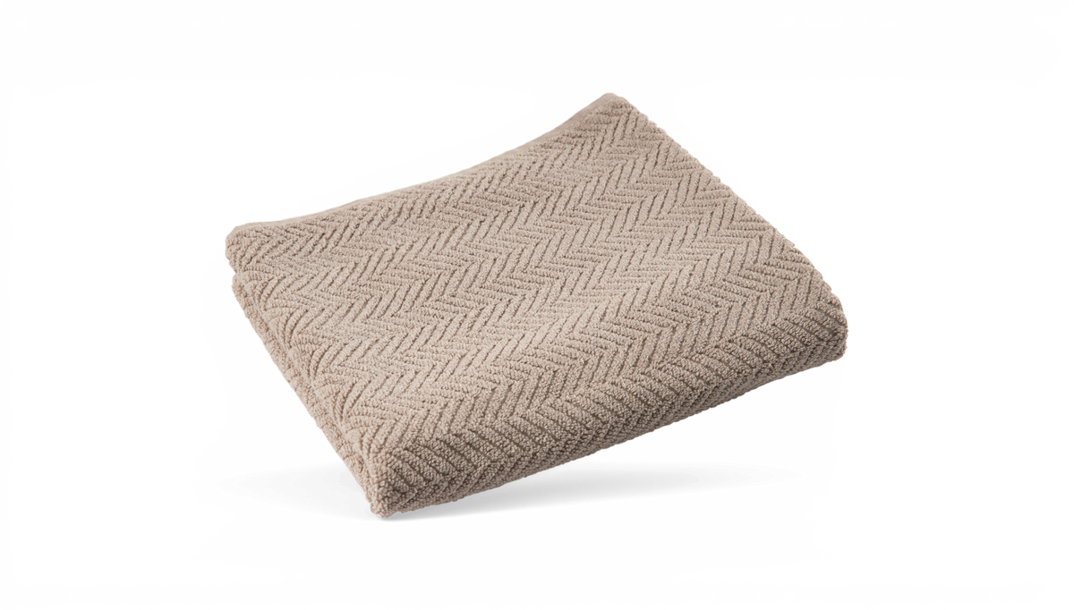 Sammenfoldet beige håndklæde med sildebensmønster.