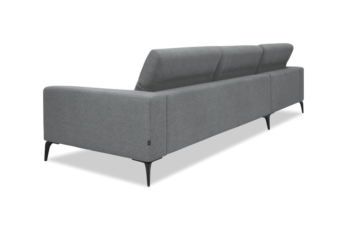 Grå moderne stofsofa set bagfra i skrå vinkel med slanke sorte ben.