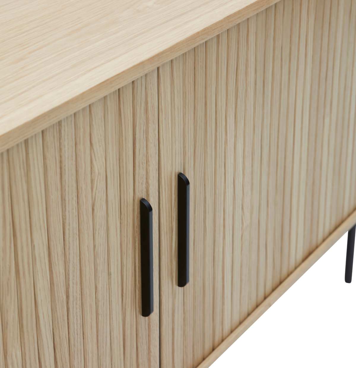 Nærbillede af et lys egetræsfineret sideboard med lodrette lameller og sorte metalgreb.