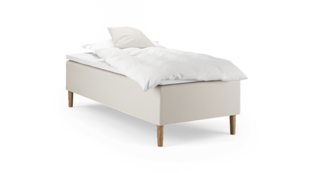 Enkelseng med beige polstret base, træben og hvidt sengetøj med pude.