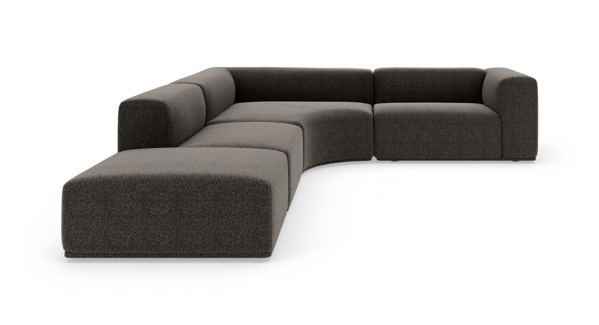Modulær L-formet sofa i mørkegråt stof på hvid studiobaggrund.