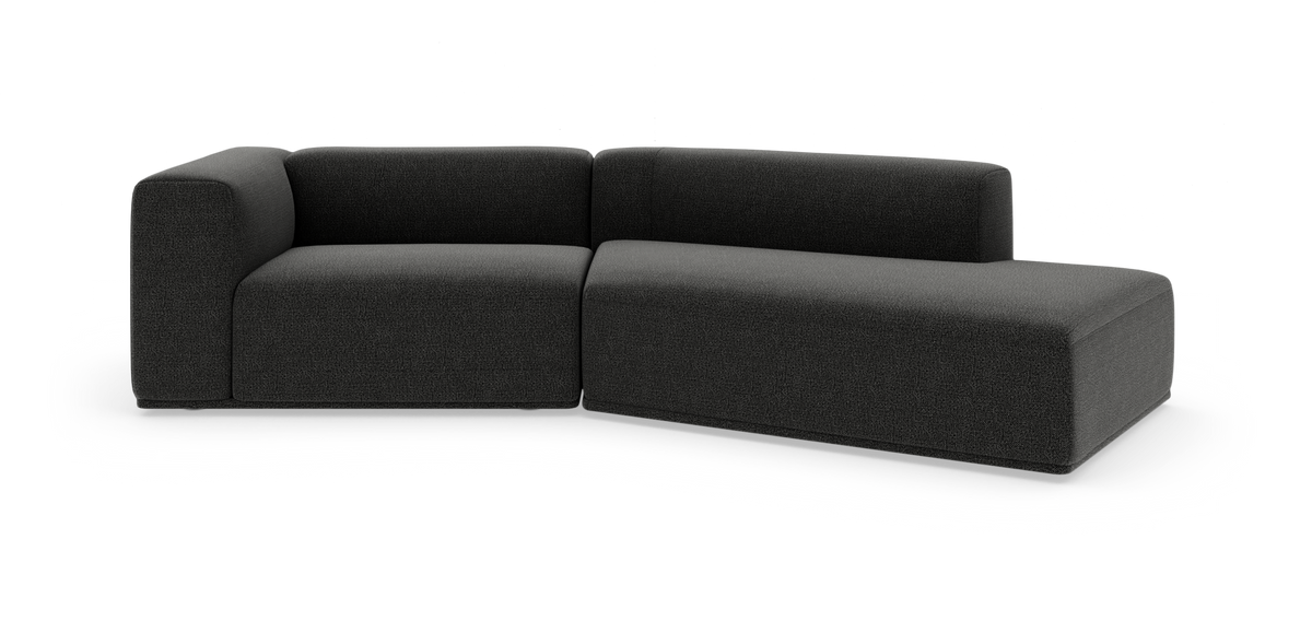 Mørkegrå L‑sofa med højrevendt chaiselong, bløde afrundede former, frilagt på hvid baggrund.