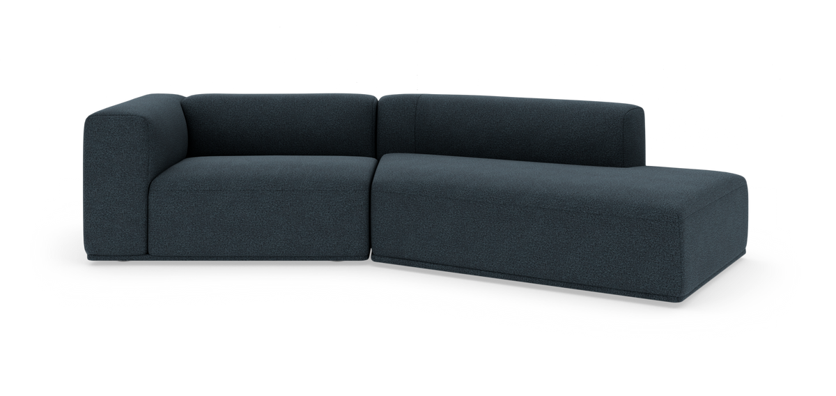 Mørkeblå modulsofa med chaiselong til højre på hvid studiebaggrund.