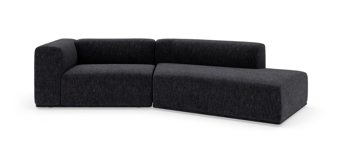 Mørkegrå modulsofa i L‑form med afrundede hjørner på hvid baggrund.