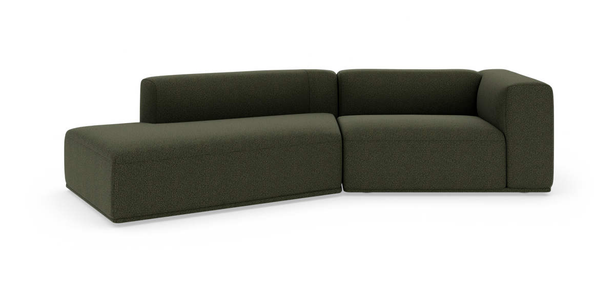 Mørkegrøn modulsofa i L‑form på hvid studiobaggrund.