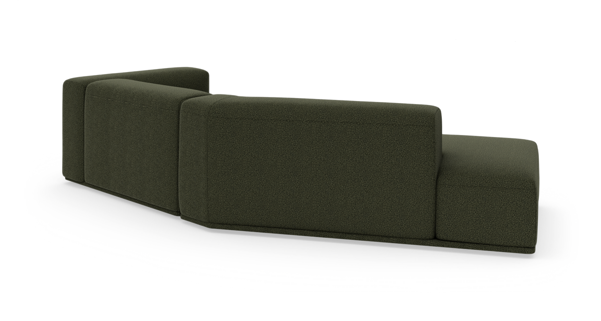 Modulsofa i mørkegrønt stof set bagfra i skrå vinkel på hvid studiebaggrund.