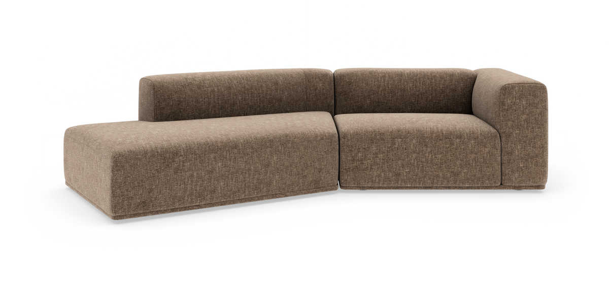 Modulær L‑sofa i brunbeige stof med afrundede hjørner og lav ryg, frilagt på hvid baggrund.