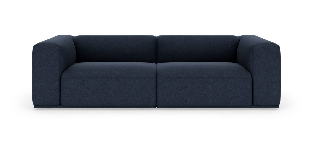 Mørkeblå, moderne modulsofa med blødt afrundede armlæn, fotograferet lige forfra på hvid studiobaggrund.