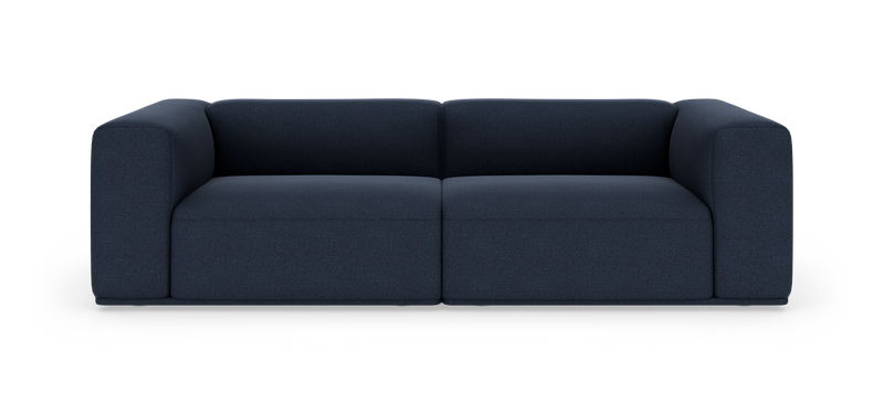 Mørkeblå, moderne modulsofa med blødt afrundede armlæn, fotograferet lige forfra på hvid studiobaggrund._ps
