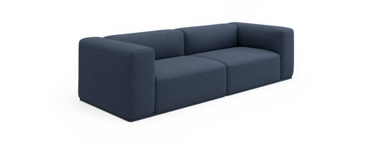 Mørkeblå moderne 2-personers sofa med tykke, afrundede kubiske armlæn og lav profil, fritlagt på sort baggrund.