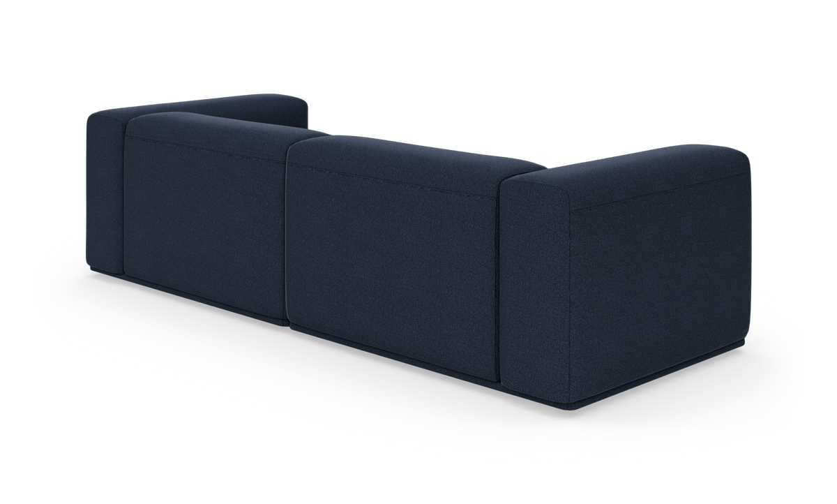 Mørkeblå modulsofa set bagfra i studie på hvid baggrund.