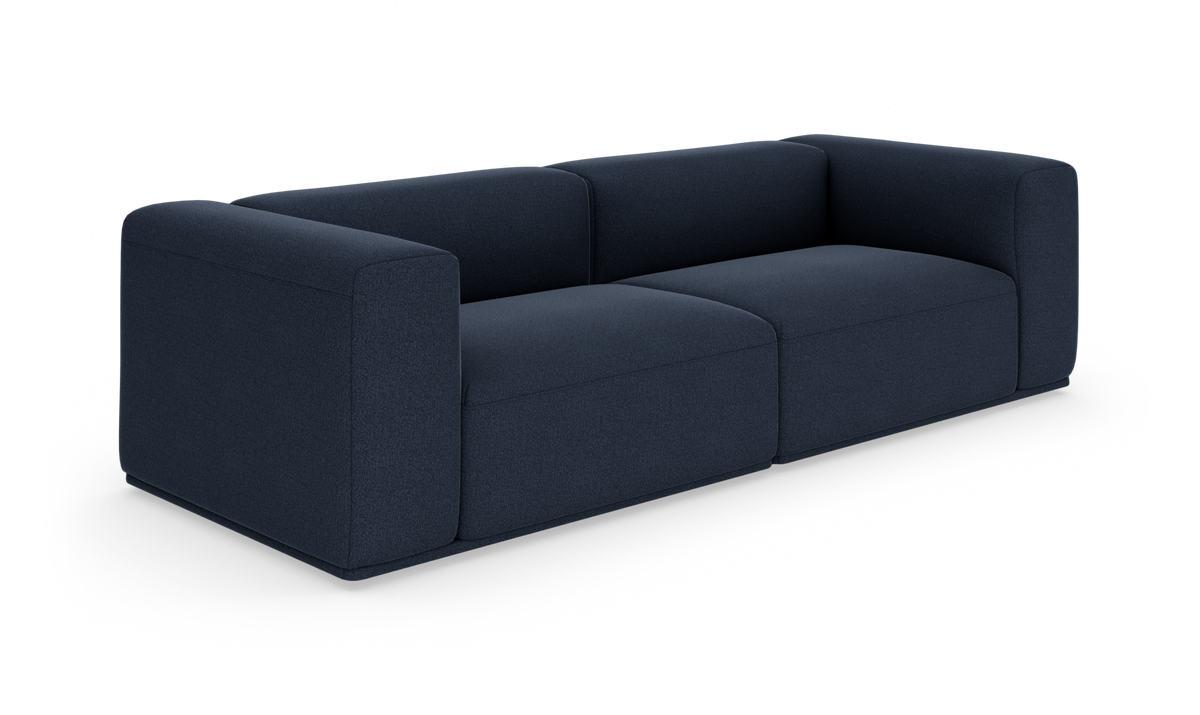 Mørkeblå, moderne tresæders modulsofa med afrundede armlæn på hvid studiebaggrund.