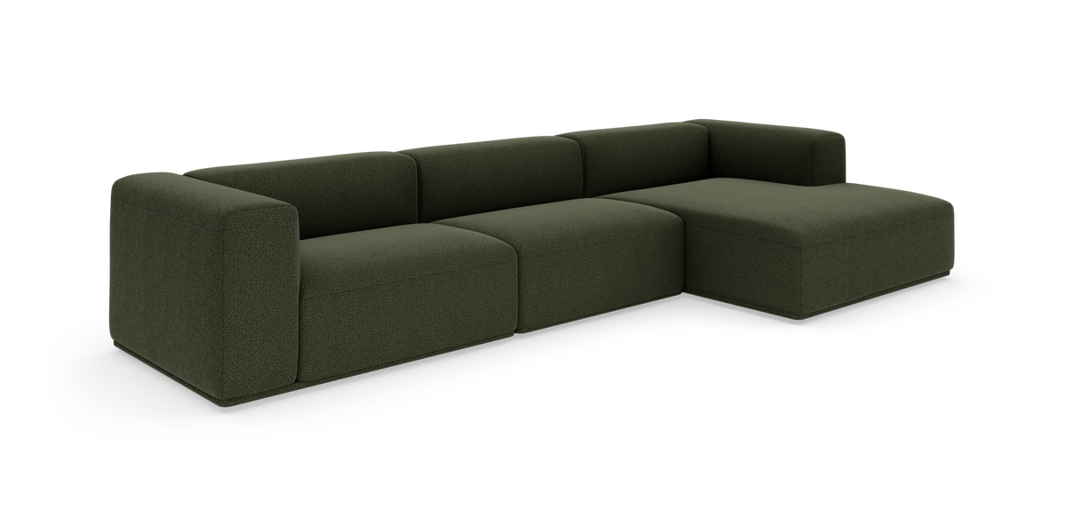 Mørkegrøn modulsofa med chaiselong til højre, fritstående mod hvid baggrund.