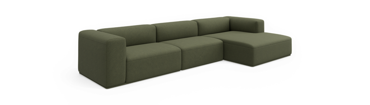 Grøn modulsofa med chaiselong, fritlagt mod sort baggrund.