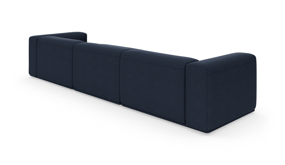 Mørkeblå modulsofa set skråt bagfra på hvid studiebaggrund.