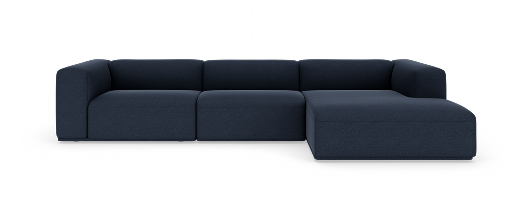 Modulær hjørnesofa i mørkeblåt stof med chaiselong til højre, frilagt på hvid baggrund.
