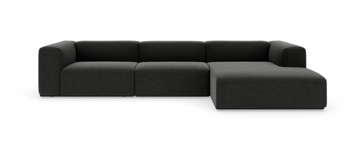 Modulsofa i mørkegråt stof med højrevendt chaiselong, vist forfra på hvid baggrund.