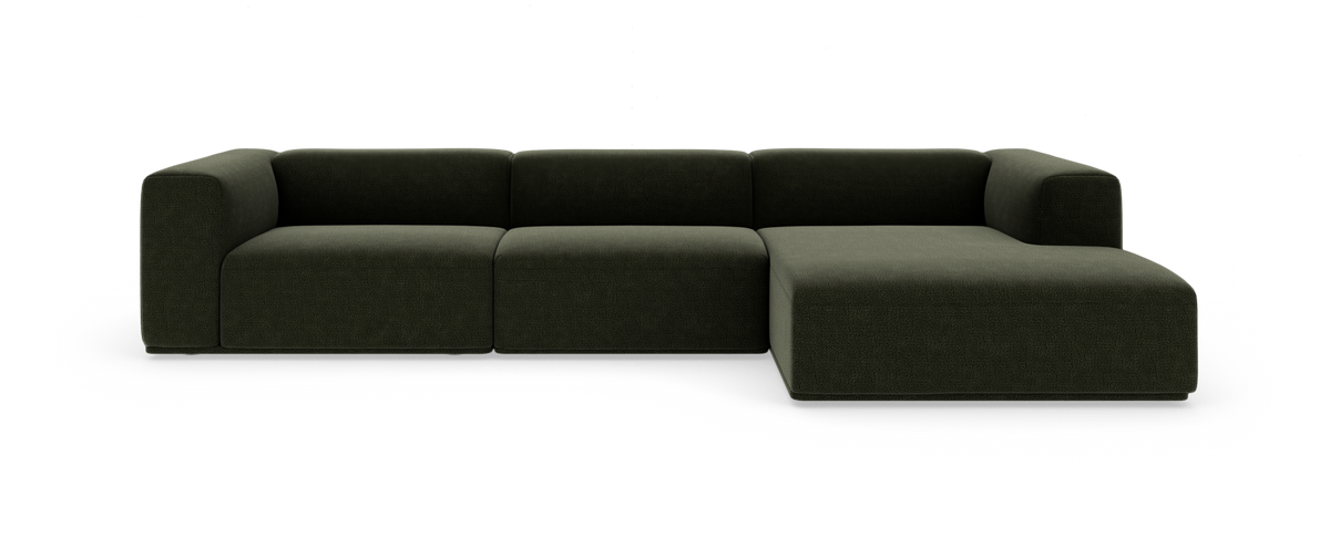 Modulær mørkegrøn hjørnesofa med chaiselong, fotograferet forfra på hvid studiobaggrund.