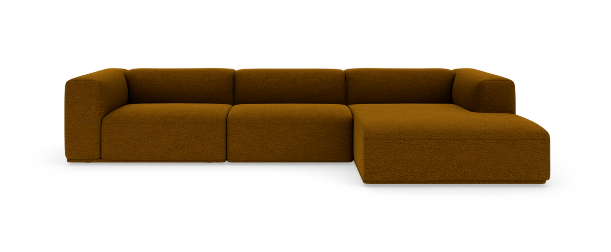 Modulsofa med chaiselong til højre i sennepsgul/brun bouclé, frilagt mod hvid baggrund.