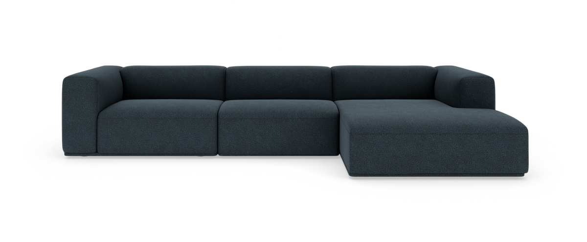Mørkeblå modulsofa med højrevendt chaiselong, set forfra mod hvid studiebaggrund.