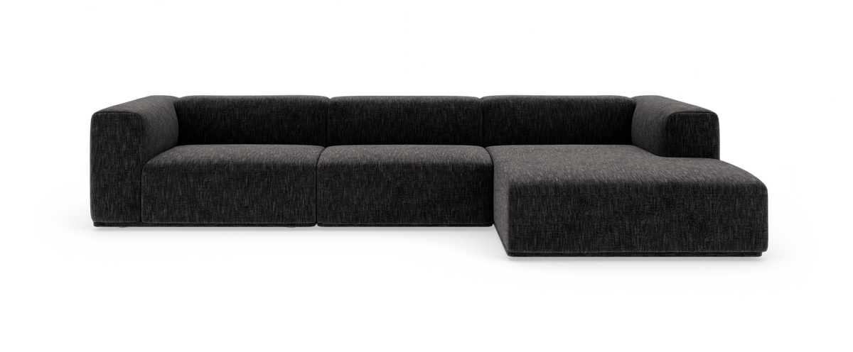 Mørkegrå modulsofa med chaiselong til højre, set forfra i studiemiljø.