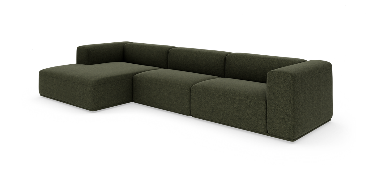 Modulsofa i mørkegrøn L-form med bred chaiselong og bløde, blokformede moduler.