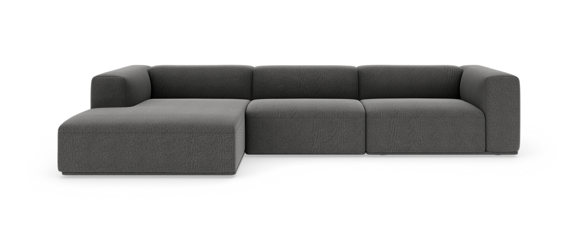 Mørkegrå modulsofa med chaiselong til venstre, fotograferet lige forfra på hvid studiobaggrund.