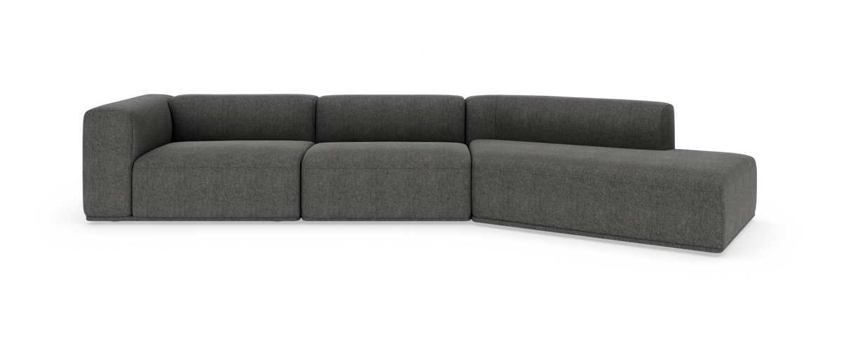 Mørkegrå modulsofa i hjørneopstilling med lav ryg og bløde blokformer, frilagt på hvid baggrund.