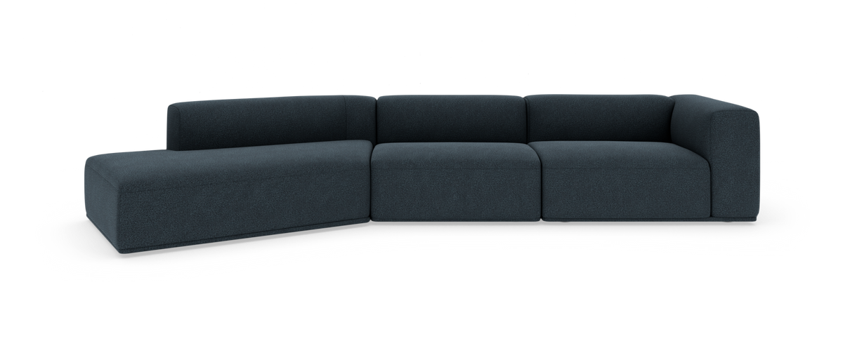 Mørkeblå modulsofa med venstrevendt chaiselong, afrundede hjørner og lav ryg, frilagt på hvid baggrund.