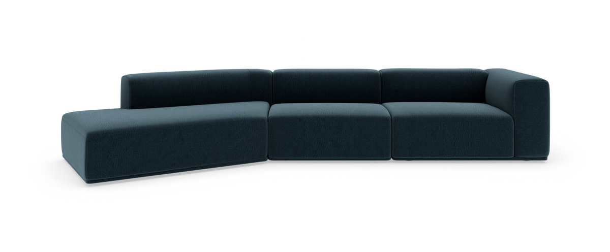 Modulsofa i mørk blågrønt stof med venstrevendt chaiselong, fotograferet lige forfra på hvid baggrund.