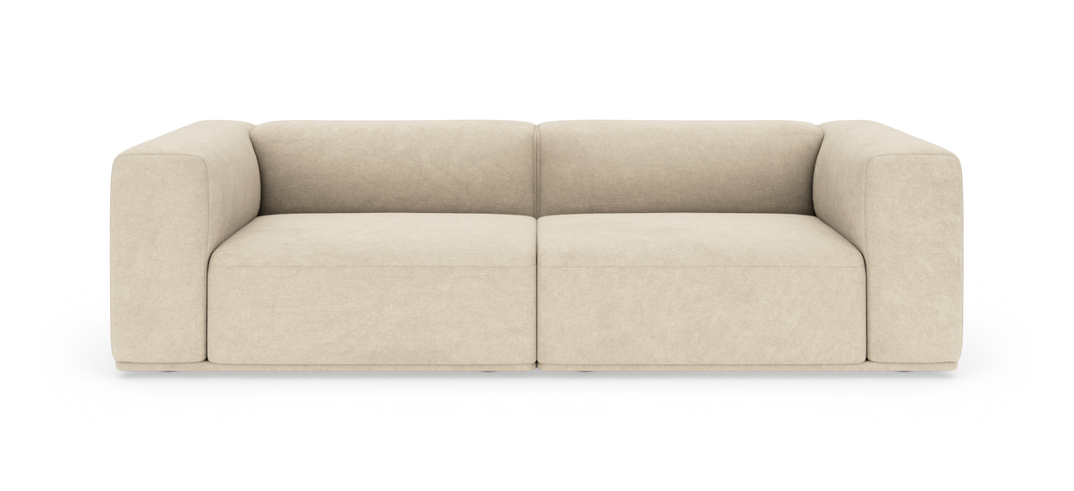 Beige tosæders sofa med afrundede, brede armlæn, fotograferet lige for mod hvid baggrund.
