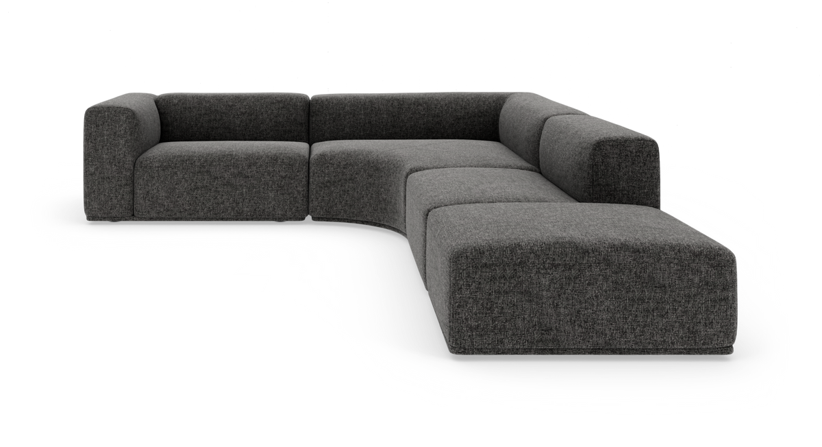 Modulær L-formet sofa i mørkegråt tekstil med bløde, afrundede former og chaiselong til højre.